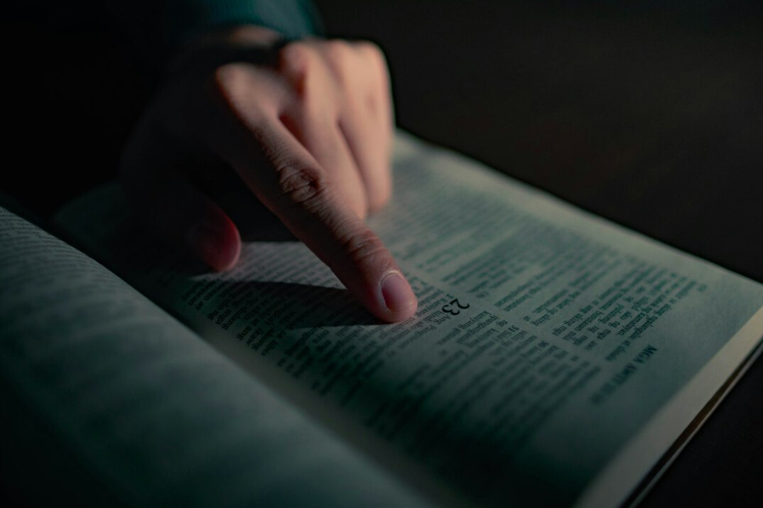Close-up of a hand reviewing a printed public record with a pen